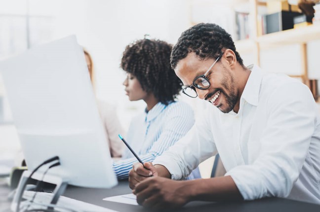 Man writing notes at a computer in an office
