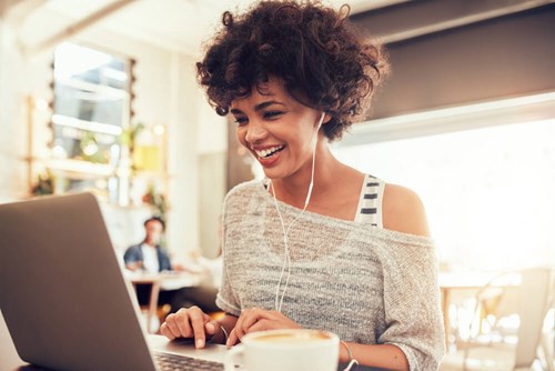women on her laptop with earphones in, in the communal office space