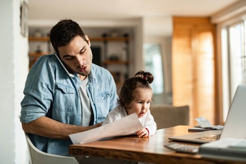 Father working from home with child on his lap.